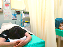 うつ伏せで電気治療を受ける男性